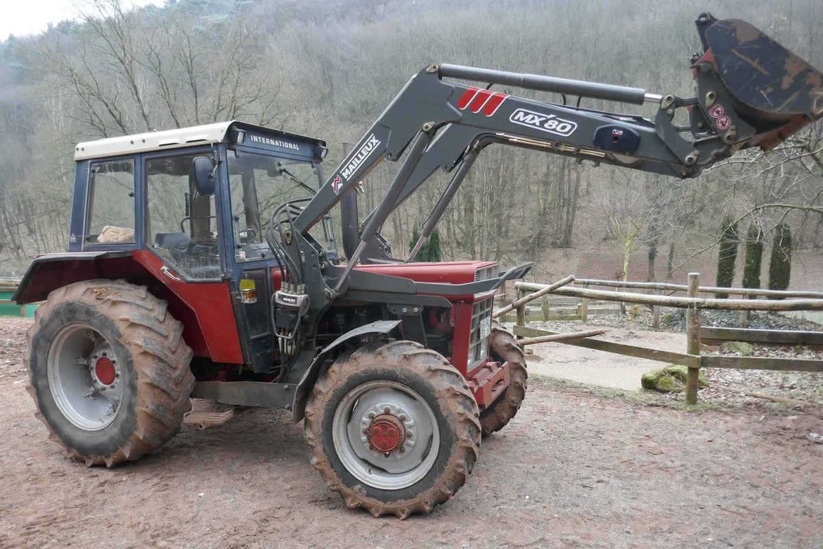 Roter Traktor mit Frontlader auf einem Hof